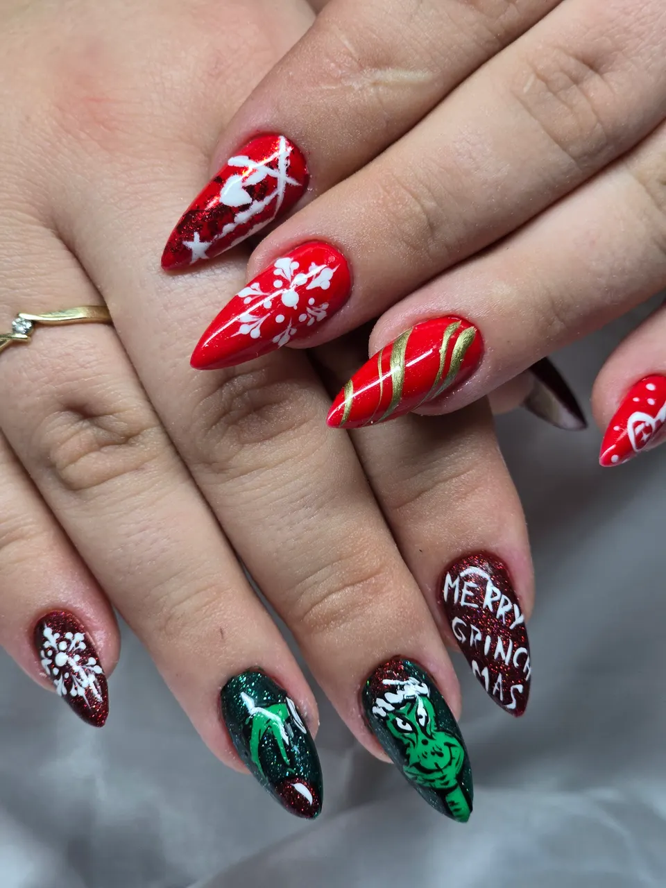 Božićni nail art s pahuljama, natpisom Merry Grinchmas i zelenim motivom